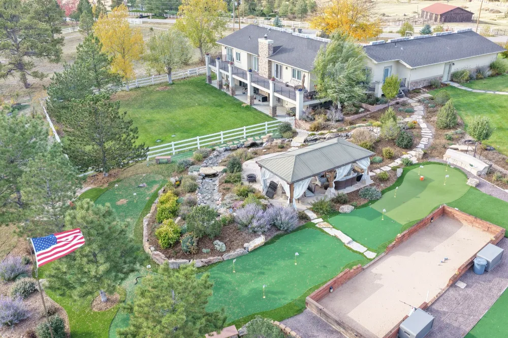 Aerial view of a home in Aurora, Colorado with a finished roof, backyard putting green and American flag.